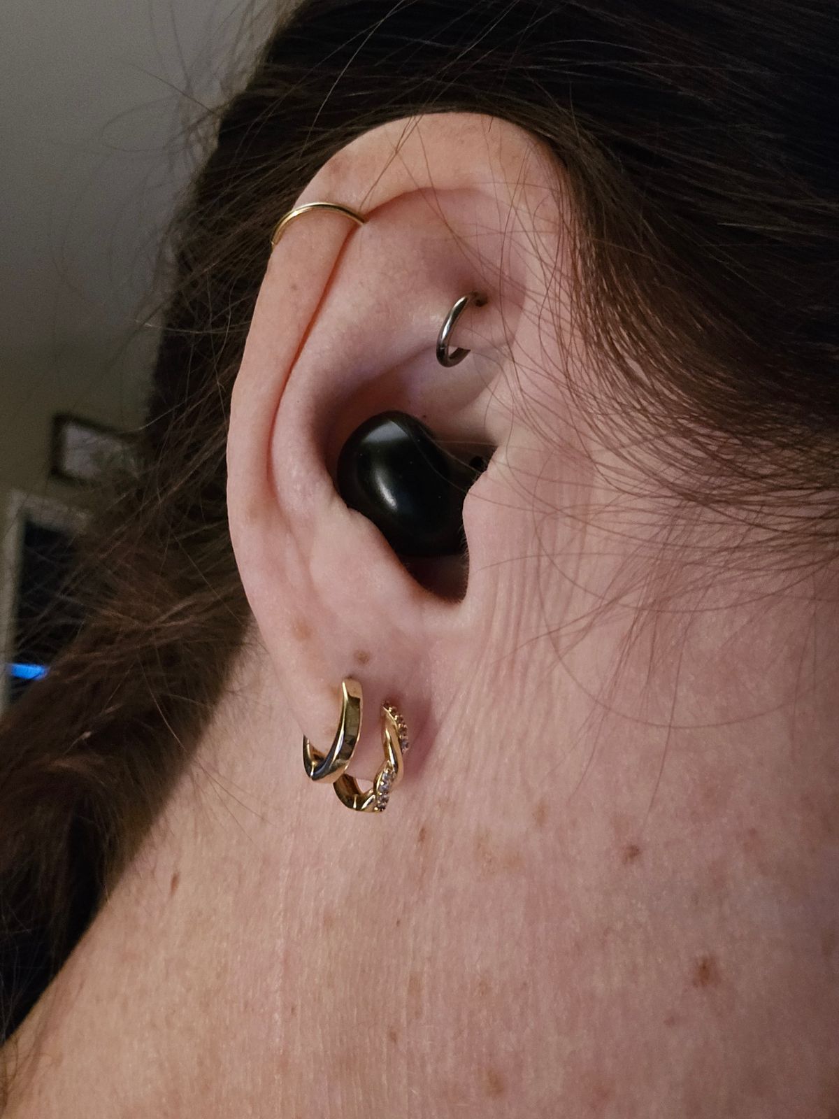 Close-up of a pierced ear wearing the black earbud resting in the outer ear