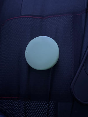 Closed off-white round charging case resting on a car seat