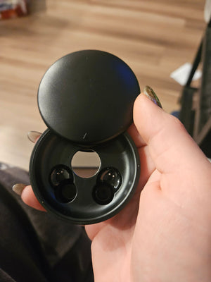 Open round black charging case with both earbuds inside