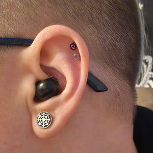Ear wearing the black earbud in daylight, square crop