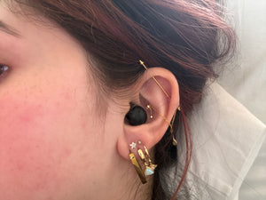 Close-up of a pierced ear wearing the black earbud